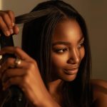 A black woman straightening her hair